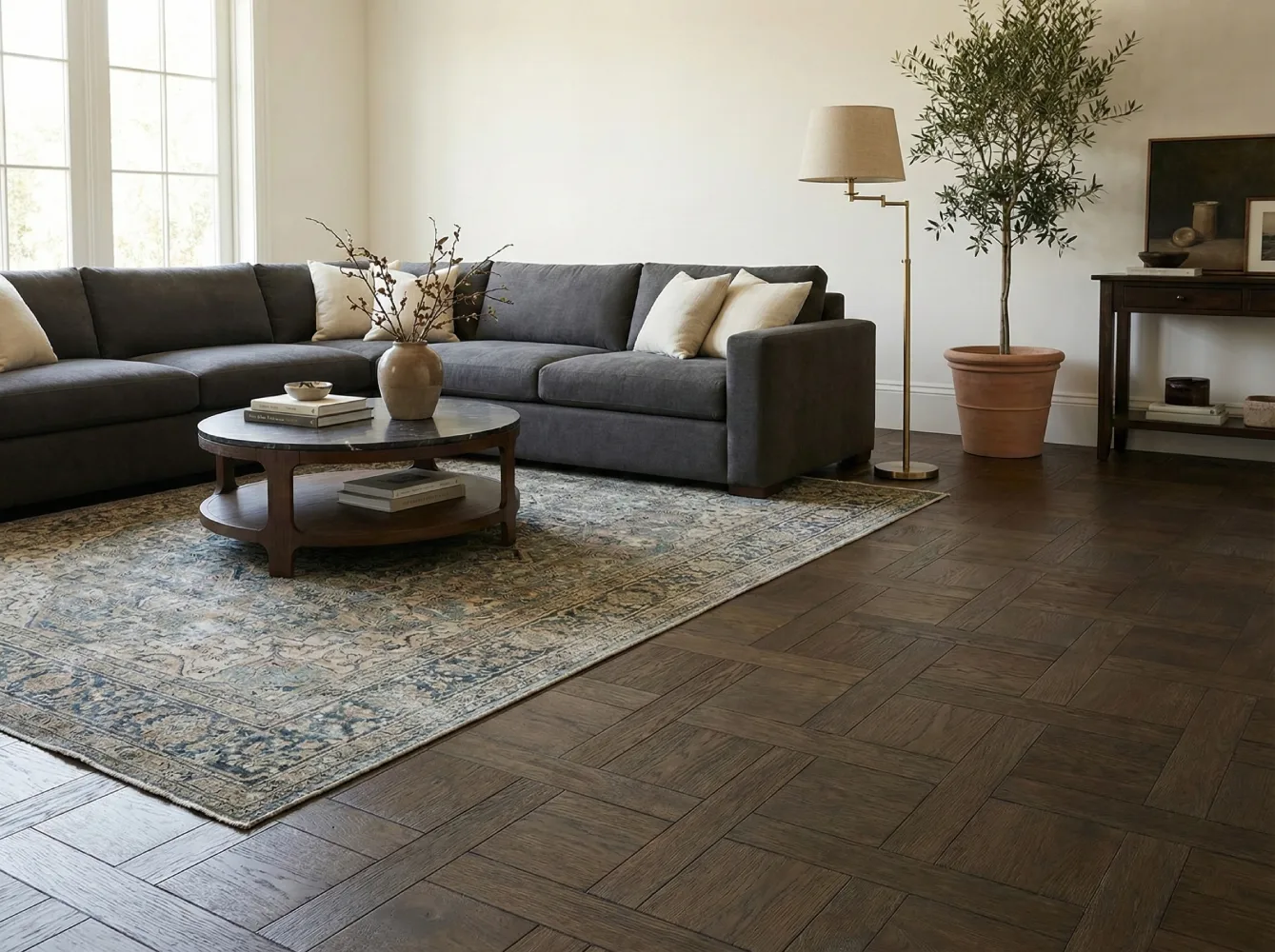 Modern living room interior featuring dark grey oak engineered flooring in a herringbone style, complementing the minimalist sofa and area rug.