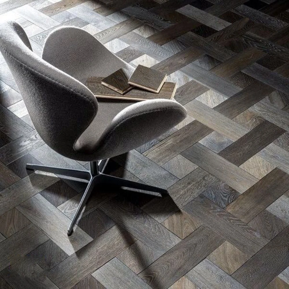 Modern grey oak narrow plank flooring with square inserts in a minimalist lounge setting with designer furniture.