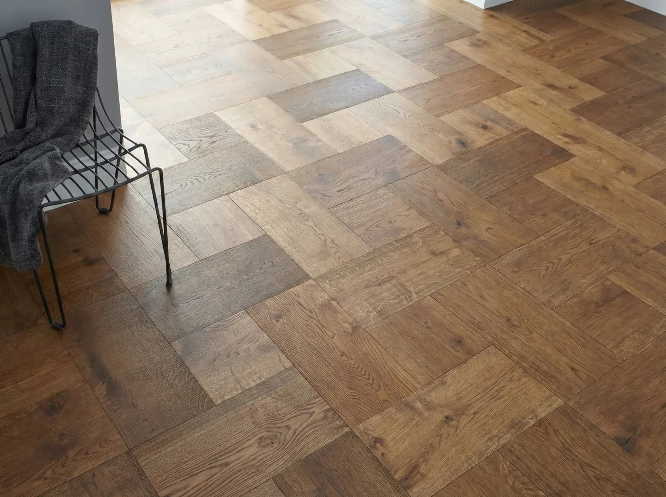 Close-up detail of natural oak parquet flooring in a herringbone pattern with square inserts, showcasing the authentic wood grain texture.